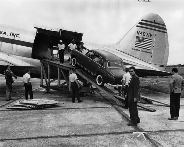 Der erste auf dem Luftwege Colon nach Guatemala beförderte Mercedes-Benz Typ 220 a wird auf dem Flughafen Aurora aus einem Lufttransporter der Aero vias Sud Americana, Inc. entladen, 1955.